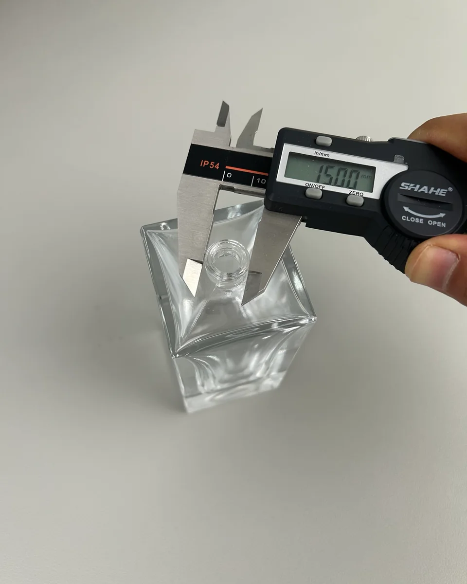 Digital caliper checking the neck of a glass perfume bottle